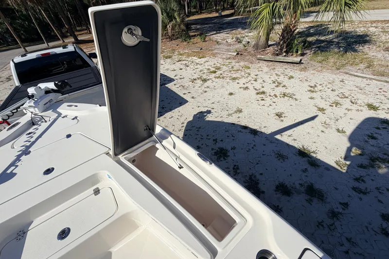 Slide: The Image of 2024 Key West 210 Bay Reef boat with open storage compartment, parked on sandy terrain. - 44