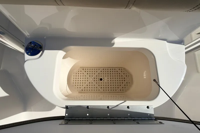 Slide: The Image of 2024 Key West 210 Bay Reef boat storage compartment with white interior and metal hinge. - 49