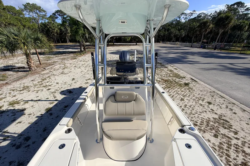 Slide: The Image of 2024 Key West 210 Bay Reef boat with seating and T-top, parked on sandy terrain. - 50