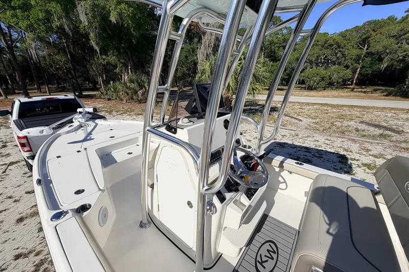 Slide: The Image of 2024 Key West 210 Bay Reef boat with T-top, parked near a truck in a wooded area. - 51