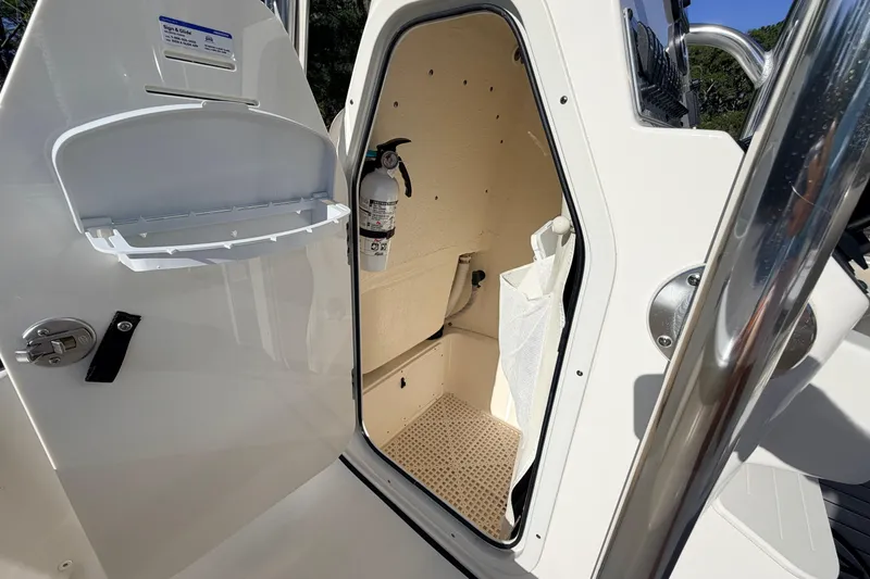 Slide: The Image of 2024 Key West 210 Bay Reef boat storage compartment with fire extinguisher and open door. - 58