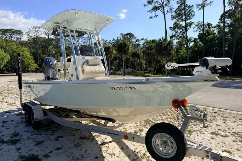 Slide: The Image of 2024 Key West 210 Bay Reef boat on trailer, parked outdoors with trees in background. - 6