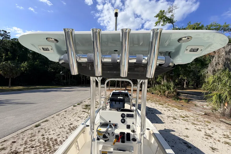 Slide: The Image of 2024 Key West 210 Bay Reef boat with T-top and rod holders, parked outdoors. - 90
