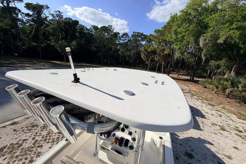 Slide: The Image of 2024 Key West 210 Bay Reef boat with rod holders, parked near a wooded area. - 91
