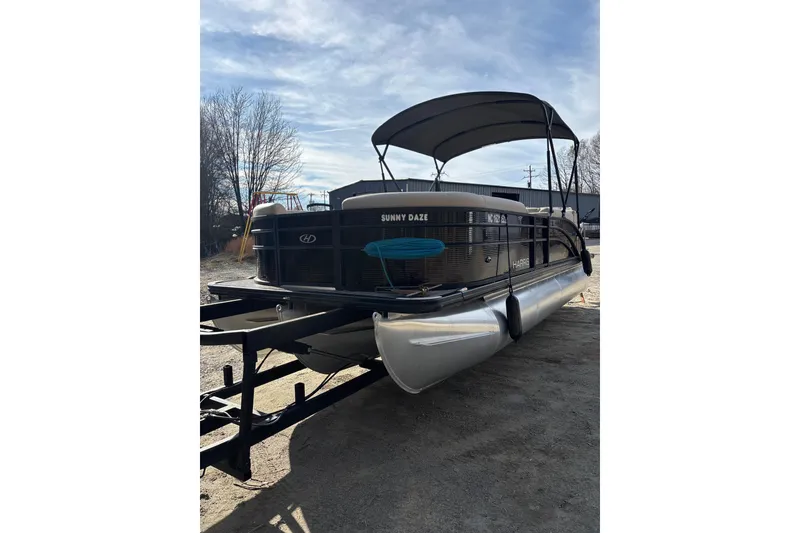 The Image of 2023 Harris Cruiser 230 pontoon boat with canopy on trailer, outdoor setting. - 0