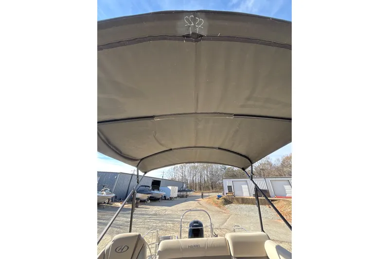 Slide: The Image of 2023 Harris Cruiser 230 boat with canopy, parked outdoors under clear sky. - 18