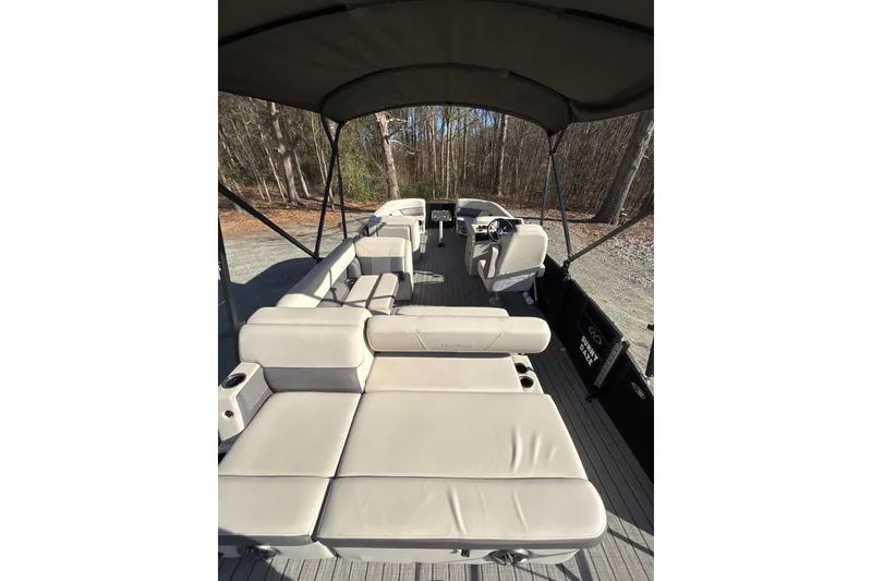 Slide: The Image of 2023 Harris Cruiser 230 pontoon boat with spacious seating and canopy in a wooded setting. - 3