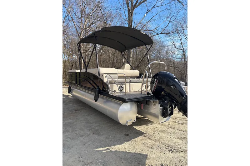 Slide: The Image of 2023 Harris Cruiser 230 pontoon boat with canopy and outboard motor, parked on dirt. - 4