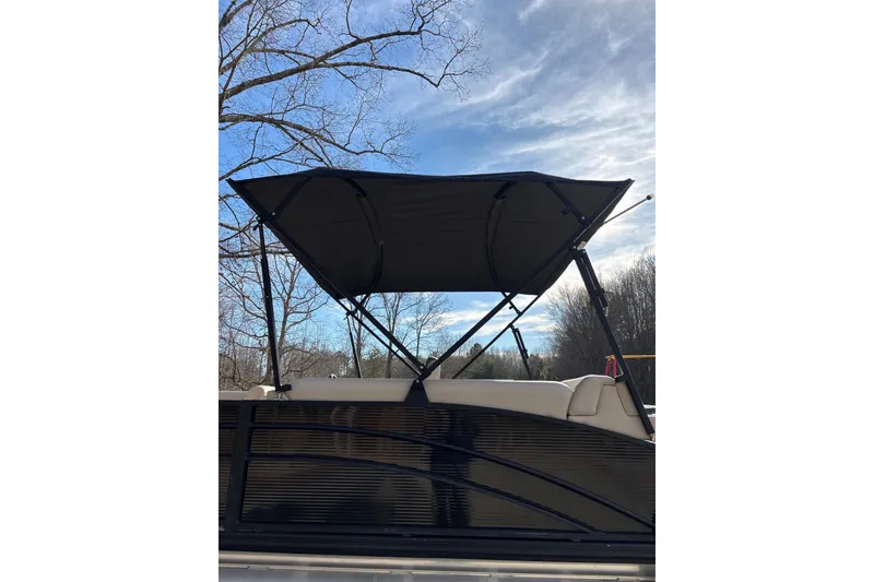 Slide: The Image of 2023 Harris Cruiser 230 pontoon boat with canopy against a clear blue sky. - 5