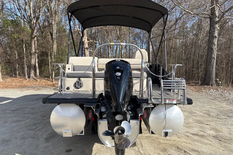 Slide: The Image of 2023 Harris Cruiser 230 pontoon boat with outboard motor, parked in wooded area. - 6