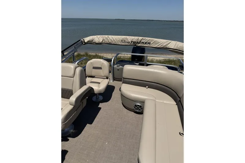 Slide: The Image of 2024 Sun Tracker Bass Buggy 18 DLX pontoon boat interior with seating, overlooking serene water. - 3