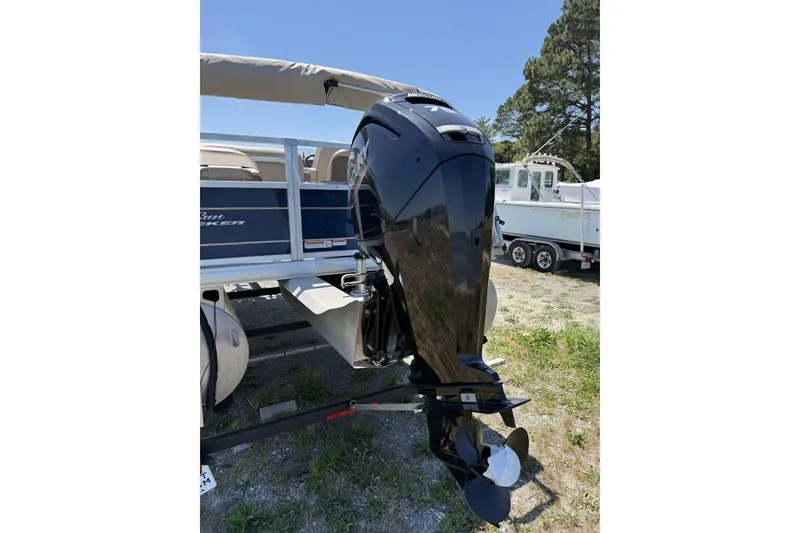 Slide: The Image of 2024 Sun Tracker Bass Buggy 18 DLX with Mercury outboard motor, parked outdoors. - 6