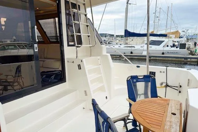 Slide: The Image of 1995 Symbol Pilothouse yacht deck with seating, table, and marina view. - 12