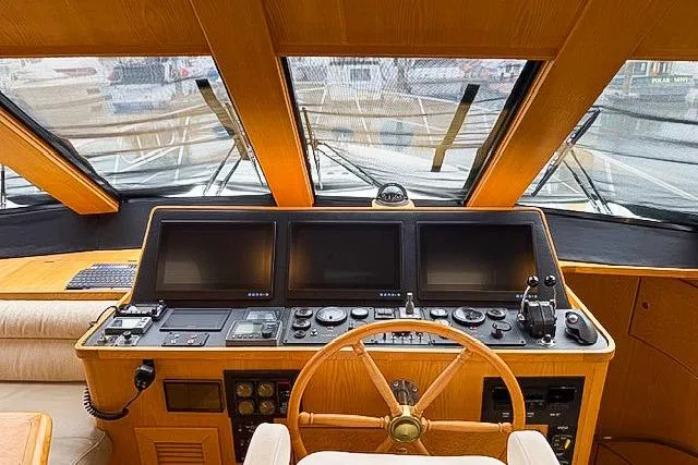 Slide: The Image of 1995 Symbol Pilothouse yacht helm with navigation screens and wooden steering wheel. - 17
