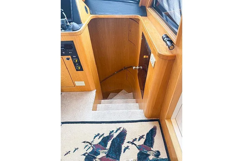 Slide: The Image of Interior of a 1995 Symbol Pilothouse yacht with wooden stairs and decorative rug. - 25