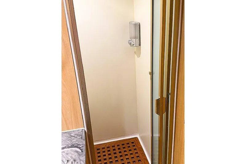 Slide: The Image of Compact shower area in a 1995 Symbol Pilothouse boat, featuring wooden flooring and dispenser. - 31