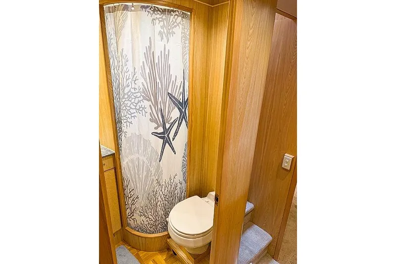 Slide: The Image of 1995 Symbol Pilothouse bathroom with shower curtain, wooden interior, and compact toilet. - 36