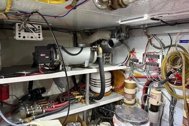 Slide: The Image of Engine room of a 1995 Symbol Pilothouse boat with various mechanical components and wiring. - 52