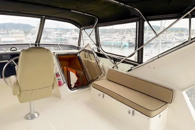 Slide: The Image of 1995 Symbol Pilothouse interior with helm seat, beige cushions, and marina view. - 7