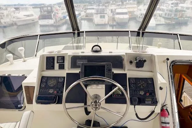 Slide: The Image of 1995 Symbol Pilothouse helm with steering wheel, navigation controls, and marina view. - 8