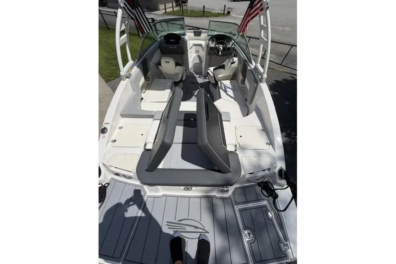 Slide: The Image of 2022 Chaparral 23 SSi boat interior with seating and steering wheel, docked outdoors. - 15