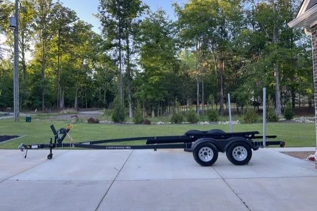 Slide: The Image of Trailer for 2022 Chaparral 23 SSi boat parked on driveway, surrounded by trees. - 18