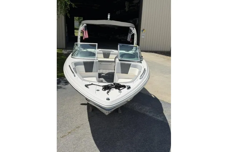 Slide: The Image of 2022 Chaparral 23 SSi boat with open bow, parked outside a storage facility. - 4