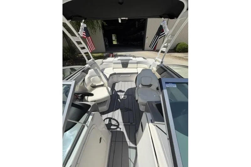 Slide: The Image of 2022 Chaparral 23 SSi boat interior with seating and steering wheel, docked outdoors. - 8