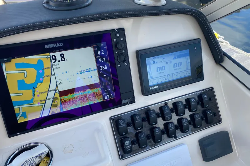 Slide: The Image of 2021 Grady-White Freedom 255 boat interior with steering wheel and control panel at marina. - 10