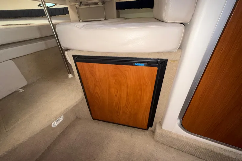 Slide: The Image of Interior of 2003 Bayliner 2655 Ciera featuring a compact wooden cabinet and beige seating. - 15