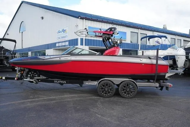 The Image of 2014 Supra Launch SA 350-550 boat in red and black on a trailer outside a dealership. - 1