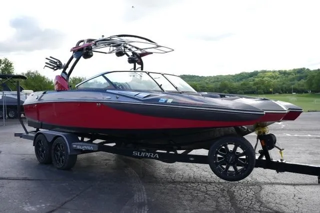 Slide: The Image of 2014 Supra Launch SA 350-550 boat on trailer, red and black design, parked outdoors. - 3