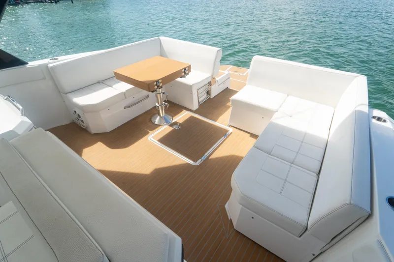 Slide: The Image of 2018 Cruisers Yachts 390 Express Coupe, spacious deck with white seating and wooden table. - 25