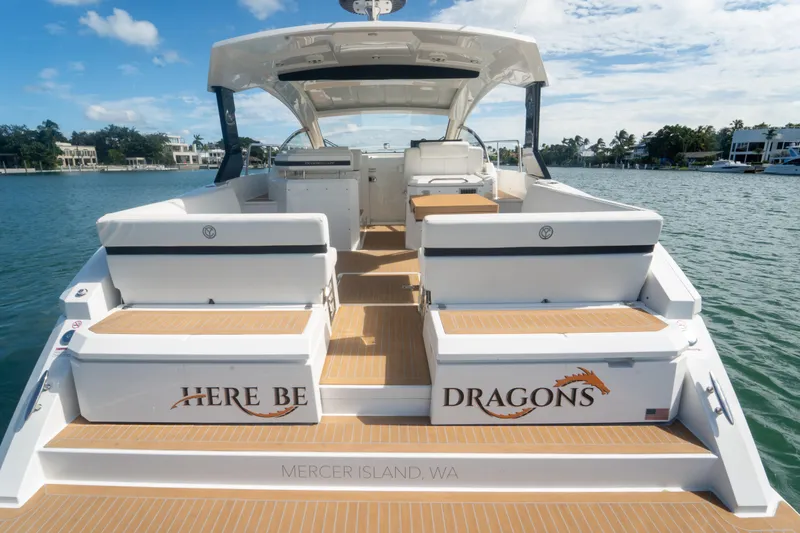 Slide: The Image of 2018 Cruisers Yachts 390 Express Coupe on water, rear view, "Here Be Dragons" text. - 27