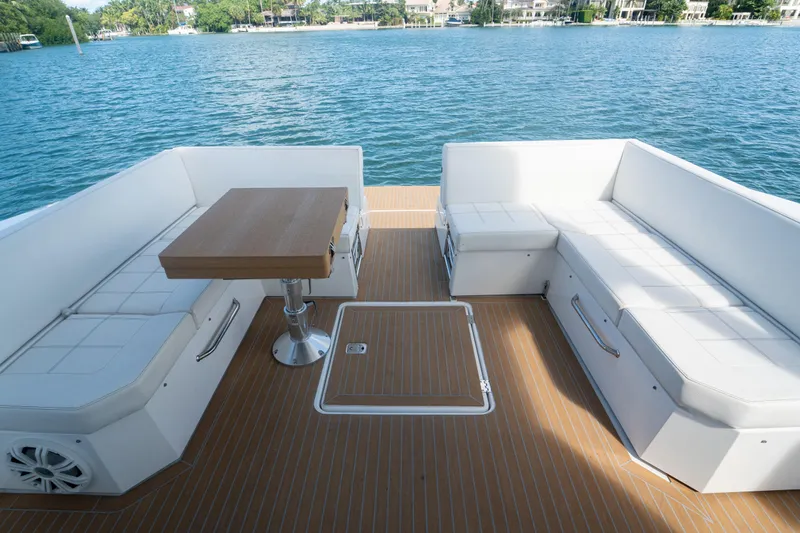 Slide: The Image of 2018 Cruisers Yachts 390 Express Coupe deck with white seating and wooden table. - 32