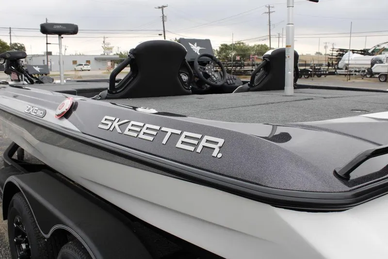 Slide: The Image of 2026 Skeeter ZXE21 boat, sleek design, gray and white finish, parked outdoors. - 17