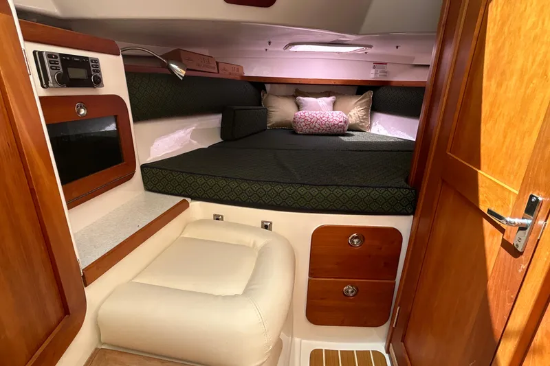 Slide: The Image of 2009 Hunt Yachts Harrier 29 cabin interior with cozy bed, wooden accents, and seating area. - 10