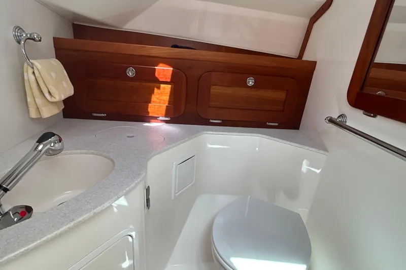 Slide: The Image of 2009 Hunt Yachts Harrier 29 bathroom with sink, toilet, and wooden cabinets. - 14