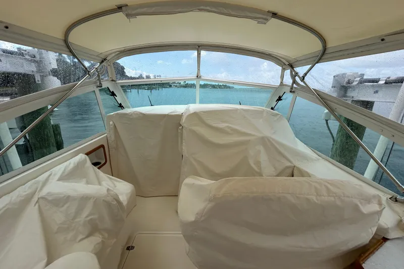 Slide: The Image of 2009 Hunt Yachts Harrier 29 interior with covered seating, overlooking a serene waterfront. - 8