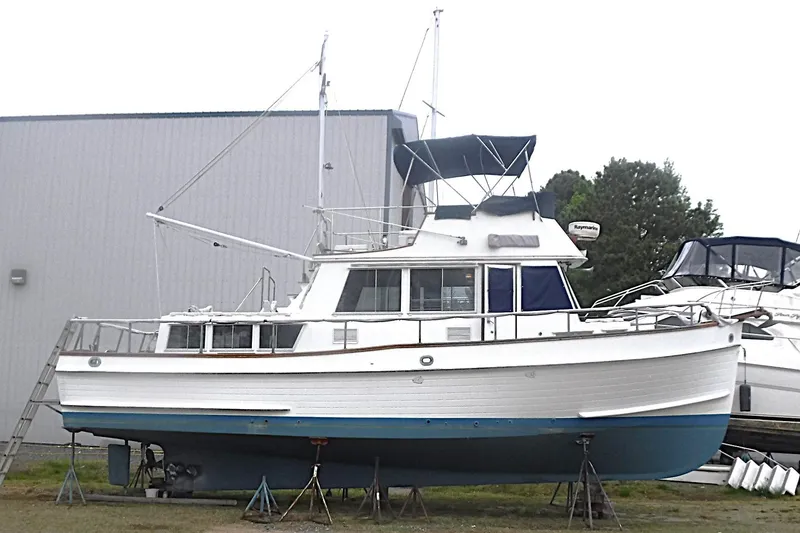 The Image of 1983 Grand Banks 36 Classic yacht on stands, white hull with blue trim, outdoor storage. - 0