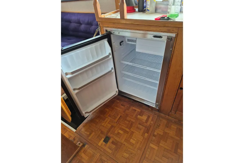 Slide: The Image of Open refrigerator inside 1983 Grand Banks 36 Classic boat, showcasing wooden interior. - 23