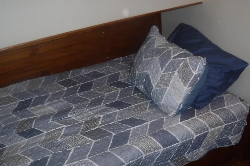 Slide: The Image of Single bed with geometric-patterned bedding in a 1983 Grand Banks 36 Classic boat cabin. - 41