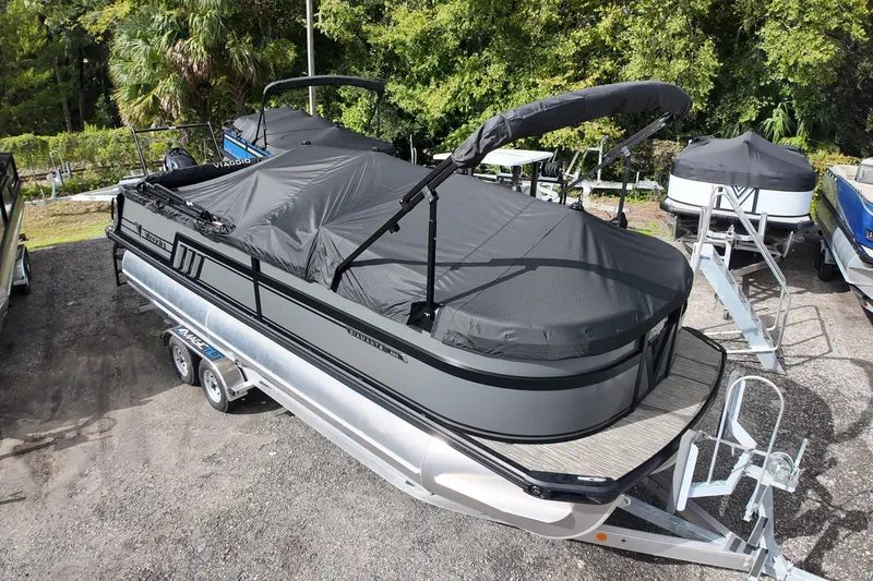Slide: The Image of 2026 Viaggio Diamante D22S pontoon boat with cover on trailer, surrounded by greenery. - 5