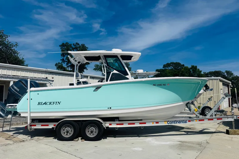 Slide: The Image of 2021 Blackfin 272 CC boat on trailer, parked outdoors under a clear blue sky. - 4
