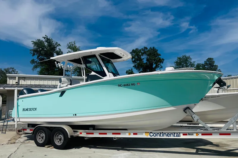 Slide: The Image of 2021 Blackfin 272 CC boat on trailer, parked outdoors under a clear blue sky. - 5