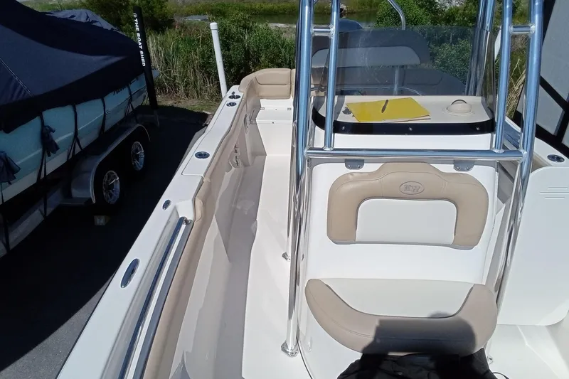 Slide: The Image of 2015 Key West 203 FS boat interior with seating and console, parked near a covered trailer. - 13