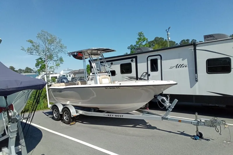 Slide: The Image of 2015 Key West 203 FS boat on trailer, parked near RV in sunny setting. - 38