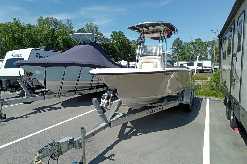Slide: The Image of 2015 Key West 203 FS boat on trailer in parking lot, surrounded by trees and RVs. - 39