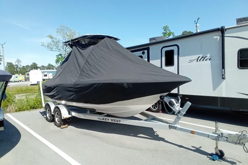 Slide: The Image of 2015 Key West 203 FS boat covered on trailer, parked beside RV. - 6