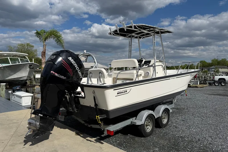 Slide: The Image of 2018 Boston Whaler 210 Montauk boat on trailer with Mercury engine, parked outdoors. - 4